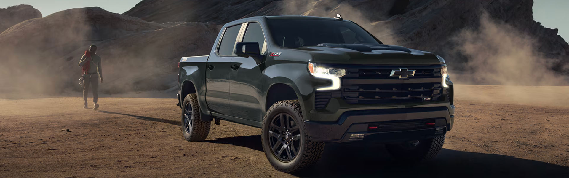 2026 Chevy Silverado Z71 off-road pickup truck in green, parked in desert terrain with LED headlights and aggressive front grille